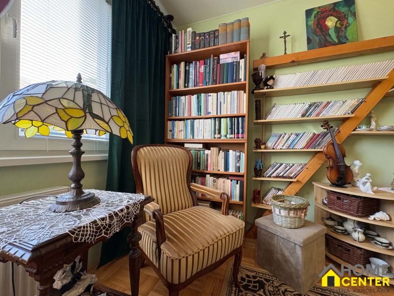 A library with many books and decorations in a 3-room apartment, a floor with a wooden decor.
