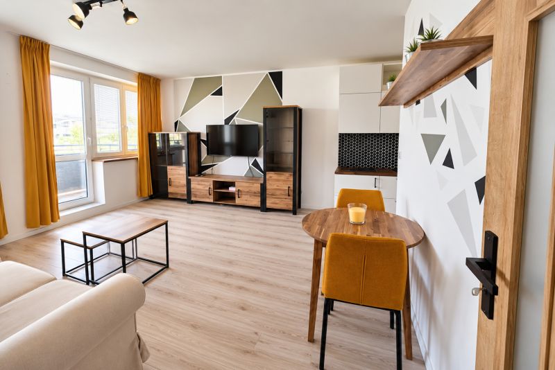 A bright living room with colorful details and a wood-patterned floor in a 2-room apartment.