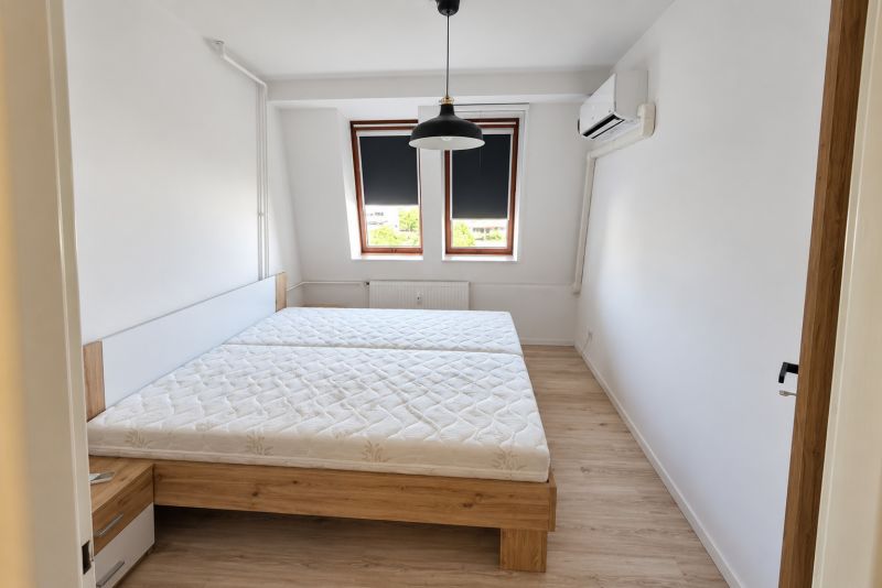 Bedroom with a bed, air conditioning, and wood-patterned flooring in a two-room apartment.