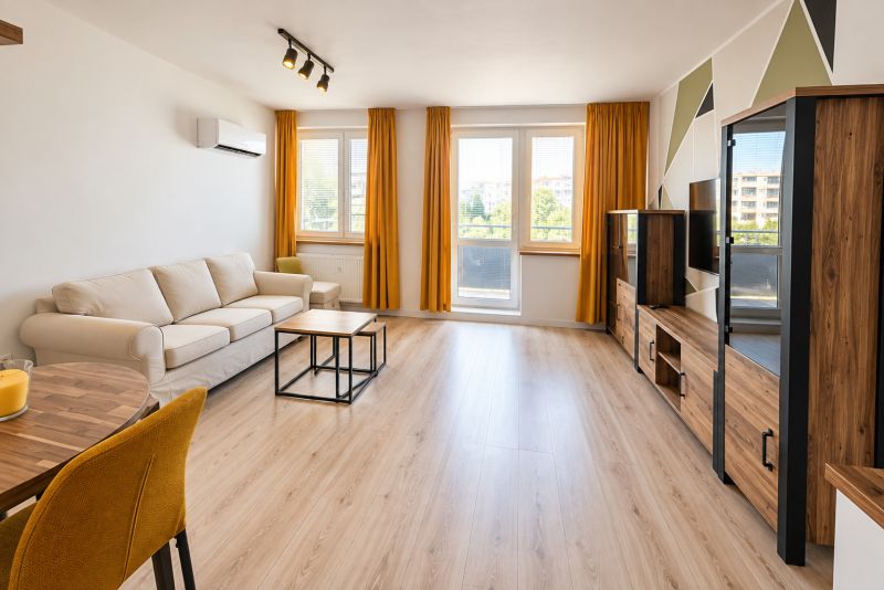 Living room with a sofa and wood-patterned flooring in a two-room apartment.