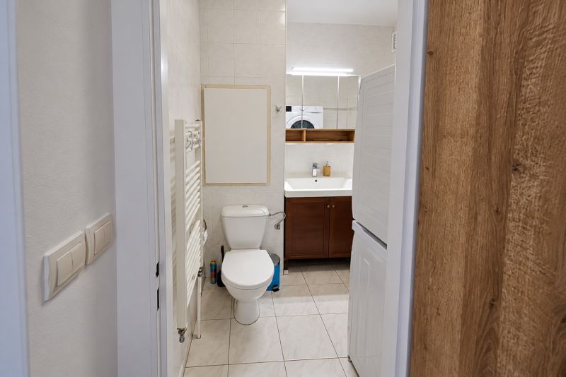 A bathroom with a sink, toilet, and washing machine in a 2-room apartment.