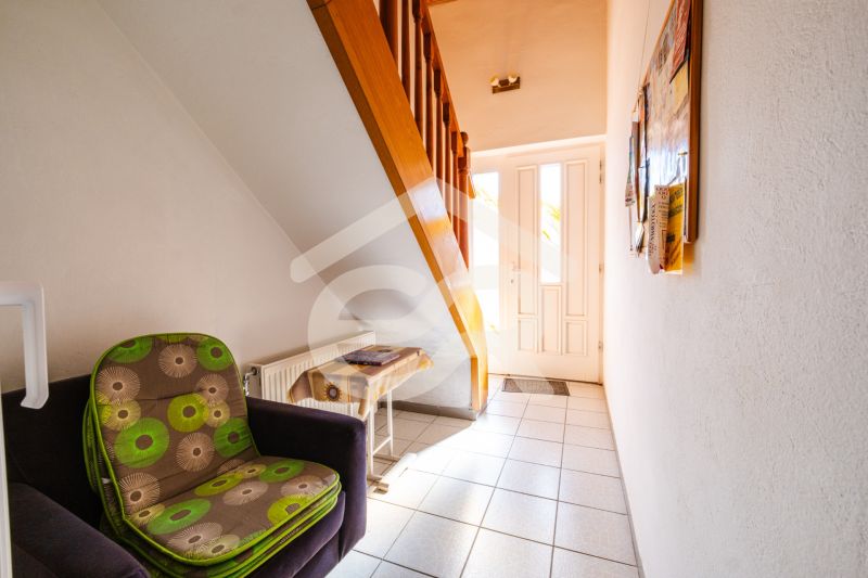 A hallway with a comfortable armchair, stairs, and a door in a family house.