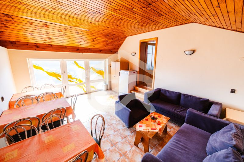 Living room in a family house with sofas, tables, chairs, and a sloped ceiling.