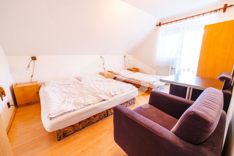 A room in a family house, bed, armchair, desk, floor with wooden decor.