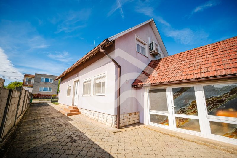 A family house on Nova Street in Podhájska with a red roof and a paved walkway.
