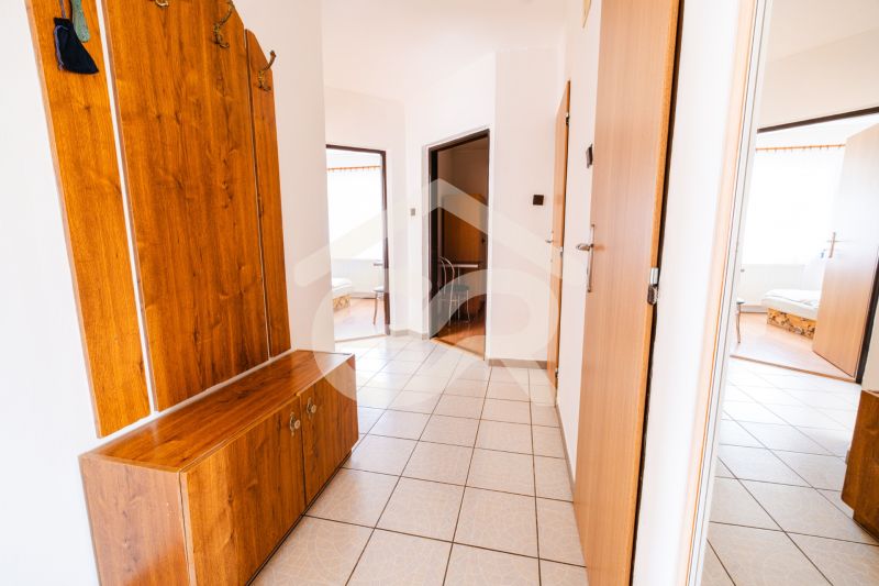 A hallway in a family house with tiles and wooden furniture.