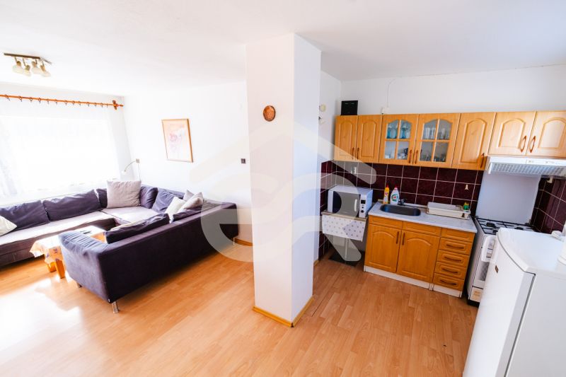 Living room and kitchen in a family house with a corner sofa and kitchen cabinets.