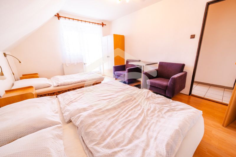 A bedroom in a family house with a double bed, chairs, and a wooden decor floor.