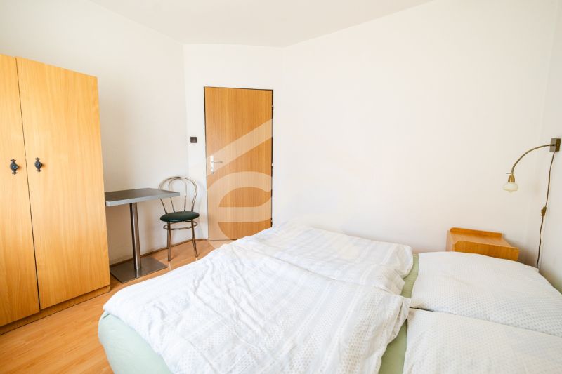 Bright bedroom with a bed, wardrobe, and wood-patterned floor in a family house.