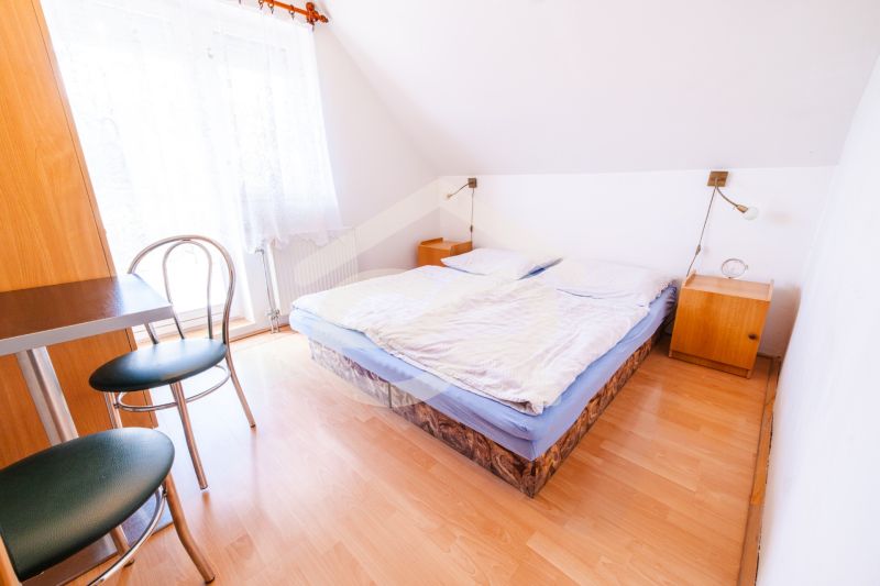 Bedroom in a family house with a double bed, a table, and a floor with a wooden decor.