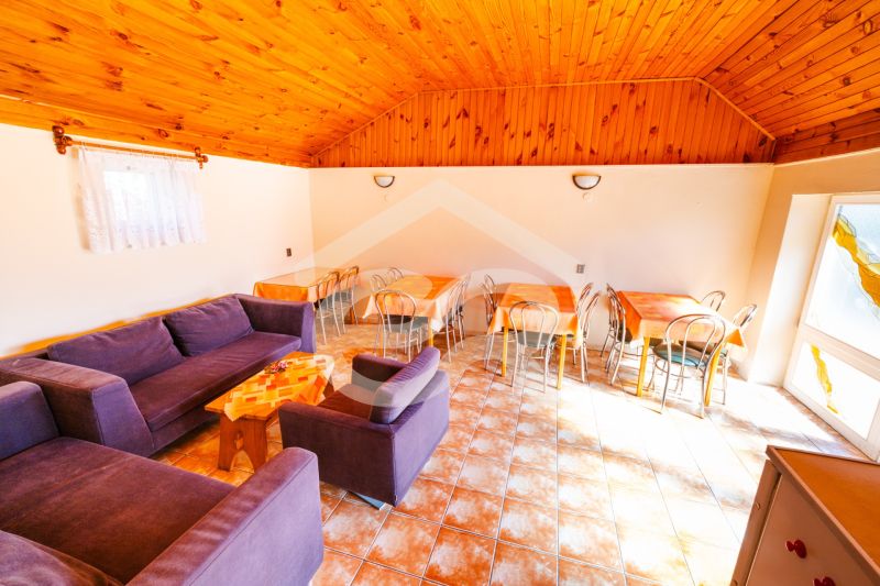 Living room with a purple sofa, dining tables, and a wooden-patterned floor.