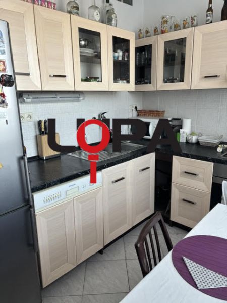 A kitchen in a two-room apartment with wooden decor furniture and light tiles.