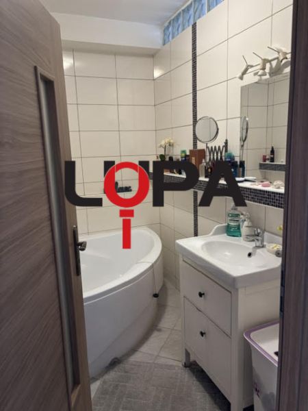 A bathroom in a 2-room apartment with a bathtub, a sink, and white tiles.