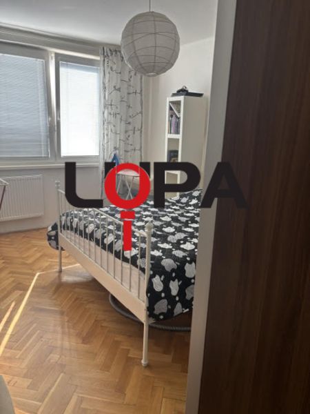 A bedroom in a two-room apartment with a bed and a wooden decor floor.