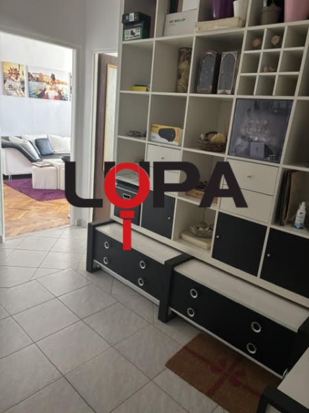A hallway in a 2-room apartment with a tiled floor and a built-in shelf.