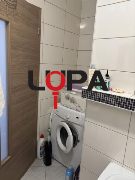 Bathroom in a 2-room apartment with a washing machine and storage space.