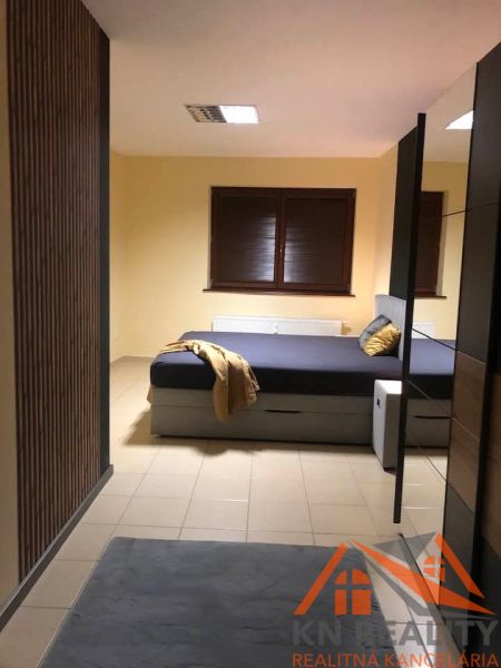 Bedroom in a 2-room apartment with a double bed and a window with dark blinds.
