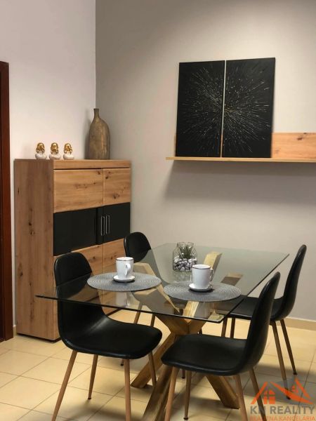 Glass table with four chairs, decorations, and a shelf in a 2-room apartment.