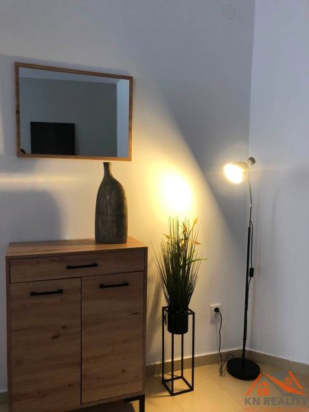 A mirror, a cabinet with a wooden floor decor, and a lamp create an atmosphere in a 2-room apartment.