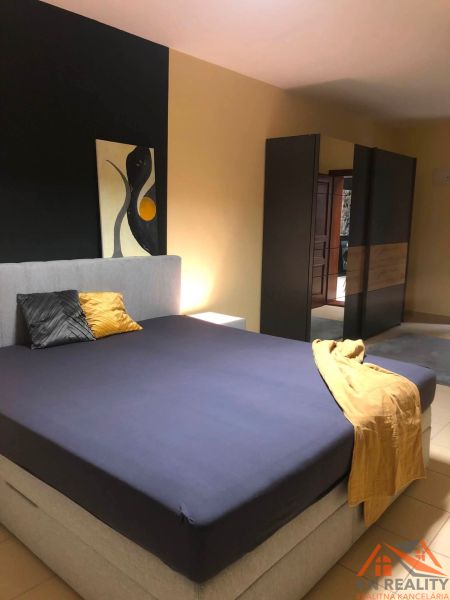 A bedroom with a double bed, a wardrobe, and abstract art in a 2-room apartment.