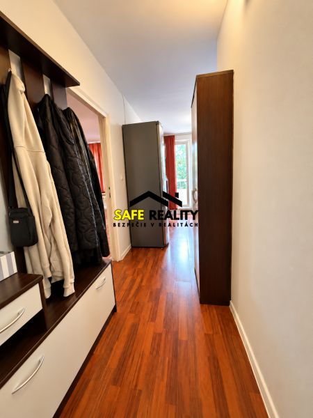 A hallway in a one-room apartment with a wooden decor floor and a wardrobe.