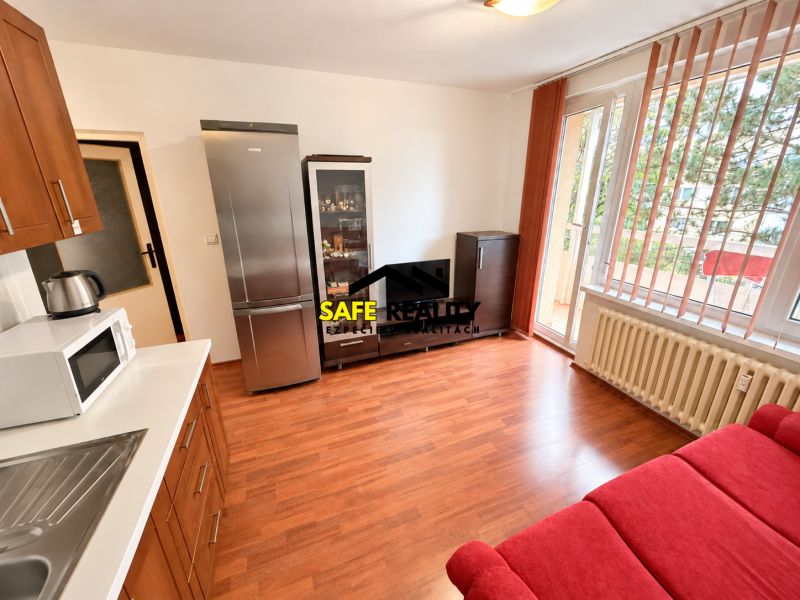 Living area of a studio apartment with a wooden decor floor and access to a balcony.