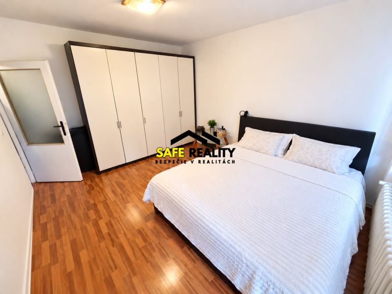 A bedroom with wood-patterned flooring and a large wardrobe in a studio apartment.