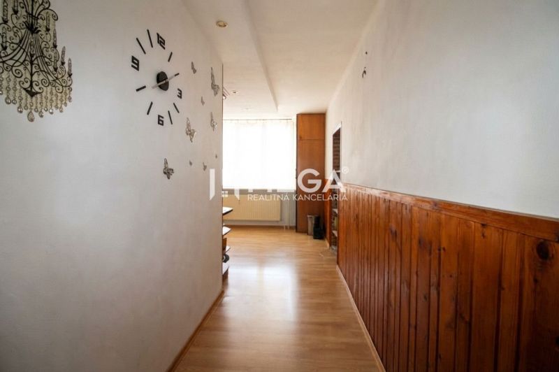 A hallway in a 3-room apartment with a wooden decor floor and wall clock.