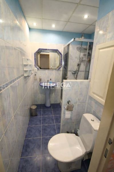 Bathroom in a 3-room apartment with blue tiles, a shower, and a mirror.