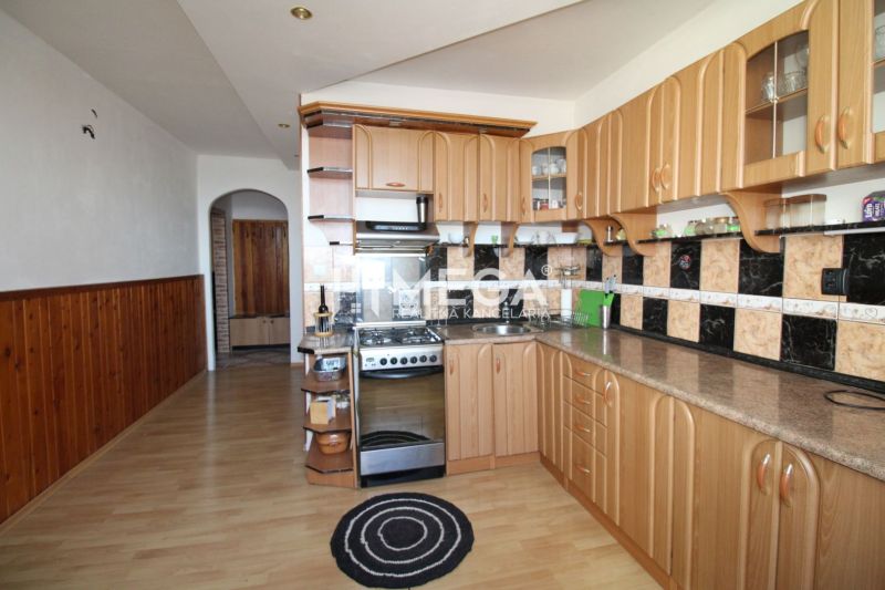 The kitchen in a 3-room apartment with a wooden decor floor and a curved cabinet.