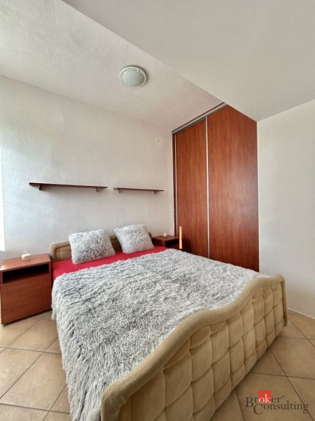A bedroom with a double bed, pillows, and a built-in wardrobe in a two-room apartment.