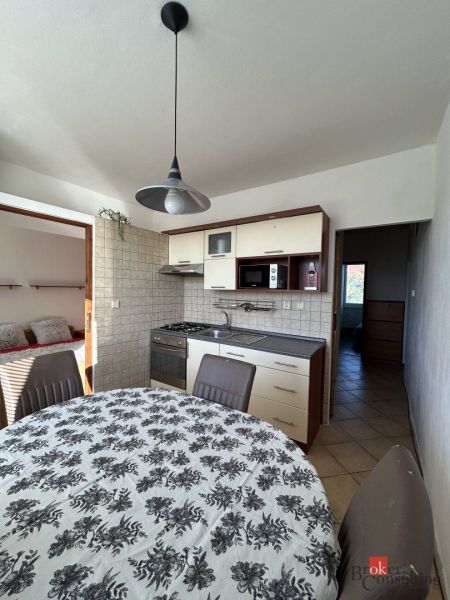 A kitchen in a 2-room apartment with a dining table and entrance to the bedroom.