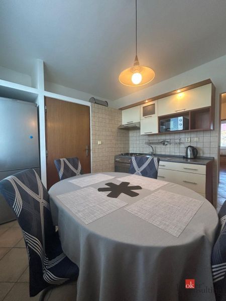 A kitchen in a 2-room apartment with a dining table and lighting.