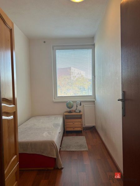 Bedroom in a 2-room apartment with a bed, nightstand, and floor with wood decor.