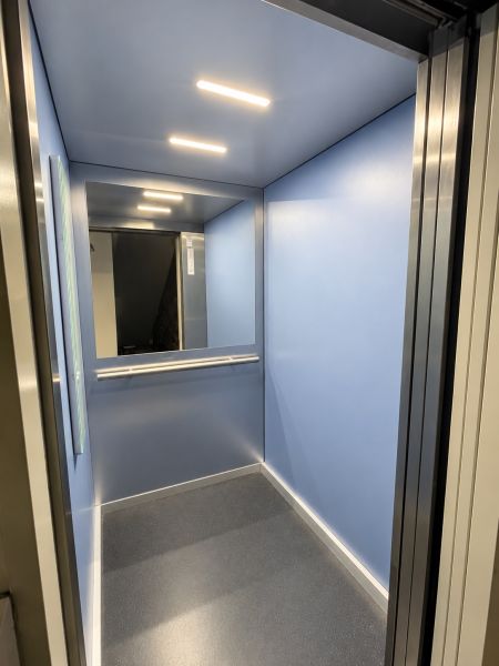 Blue elevator cabin with lighting and a mirror on the back wall.