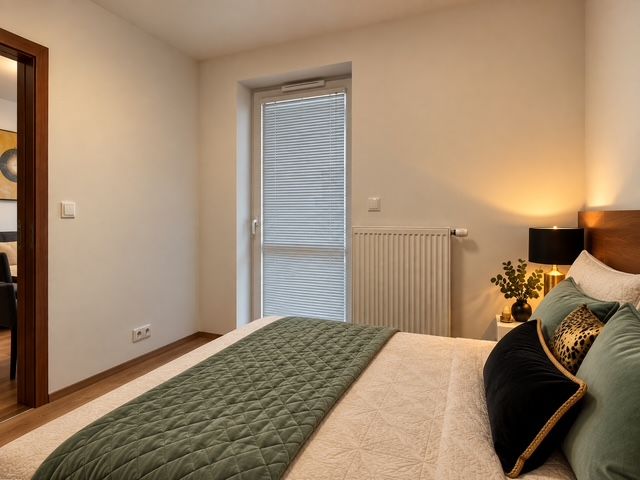 A bedroom in a two-room apartment with a green bedspread and a wooden decor floor.