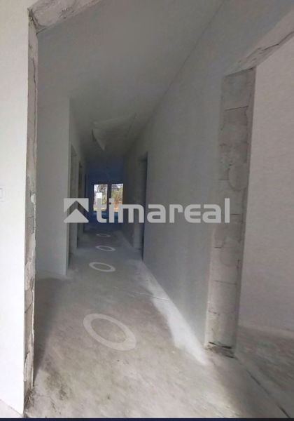 A hallway in a family house with an unfinished floor and bare walls.