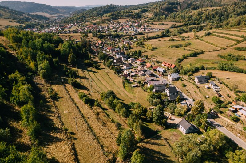 Aerial view of houses and meadows in Čierny Balog, Školská Street surrounded by recreational land.