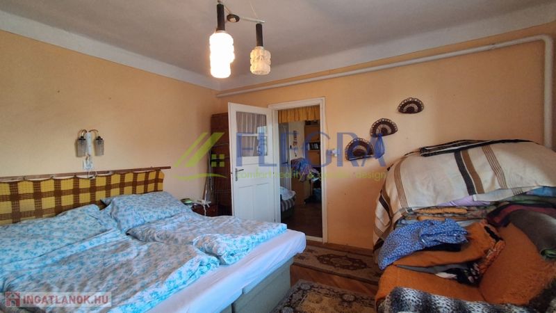 Bedroom in a family house with a double bed, blankets, and pendant lighting.