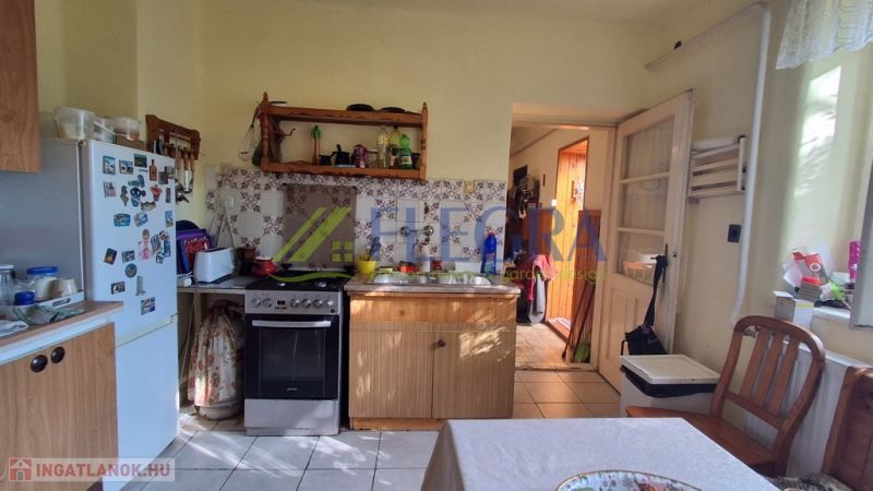 A kitchen in a family house with wooden furniture, a refrigerator, and an electric stove.