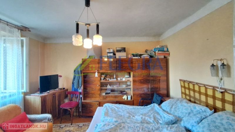 A room in a family house with furniture, a bed, and a television, simple interior.