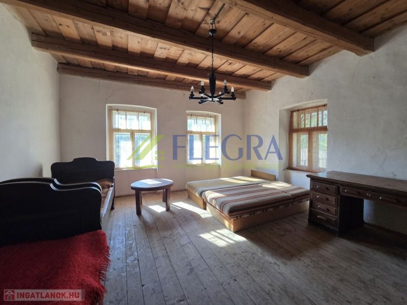 A bedroom in a family house with a wooden ceiling and a floor with a wooden decor.