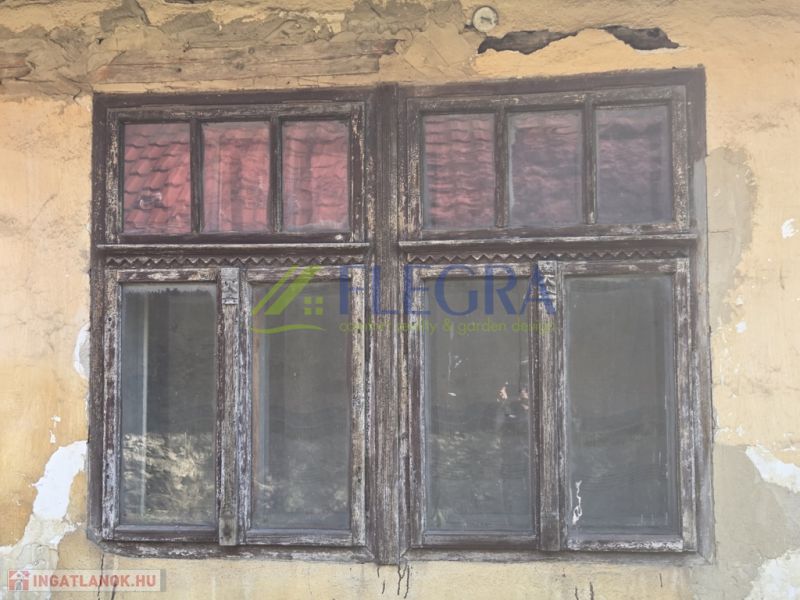Peeling plaster and an old wooden window on a family house in Hejce.