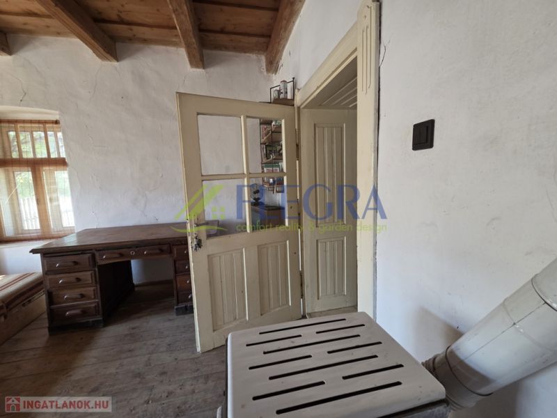 Interior of a family house with a massive table and a rustic wooden ceiling.