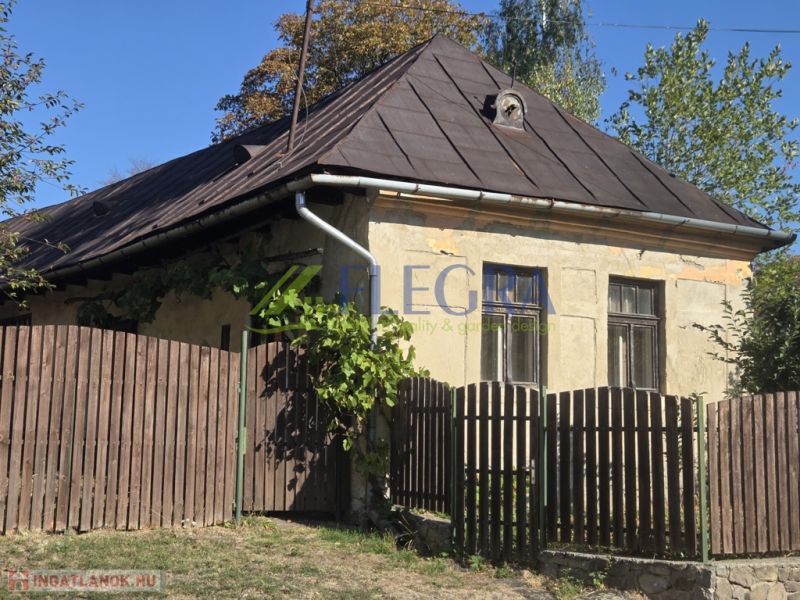 An older family house in Hejce with a sloped roof and a wooden fence.
