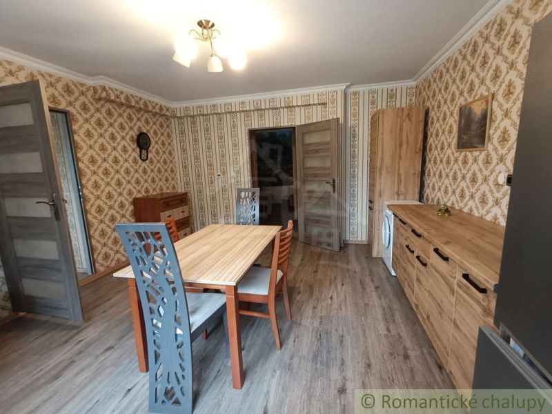 Dining room in a family house with patterned wallpaper and wooden decor flooring.