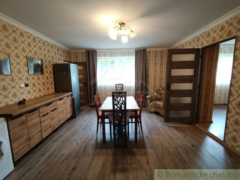 A dining room in a family house with wallpaper and a wooden decor floor.