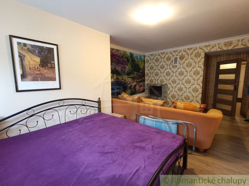 A bedroom in a family house with a purple blanket, a sofa, and a fireplace.