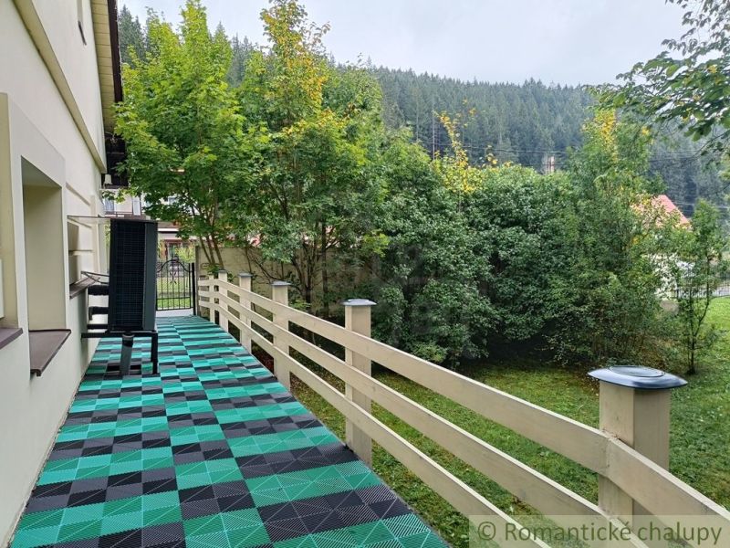 The terrace of the family house in Staškov leads to a landscaped garden with lush vegetation.