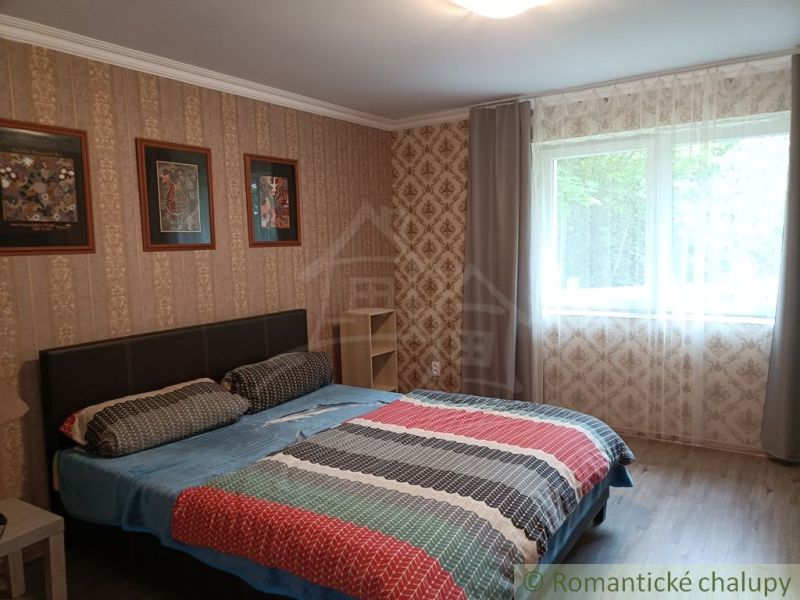 Bedroom in a family house with a double bed, window, and decorative wallpapers.
